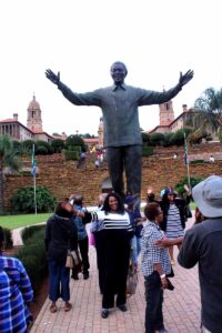 Tourists posing by large open-armed bronze statue